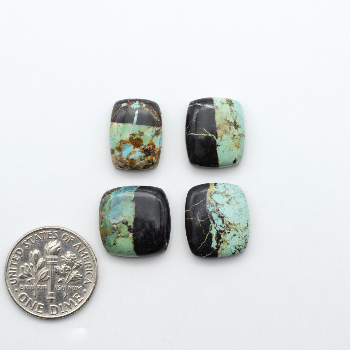 Black Jack turquoise cabochons, blue-green color with black matrix, polished stones on a white background with a US dime for scale