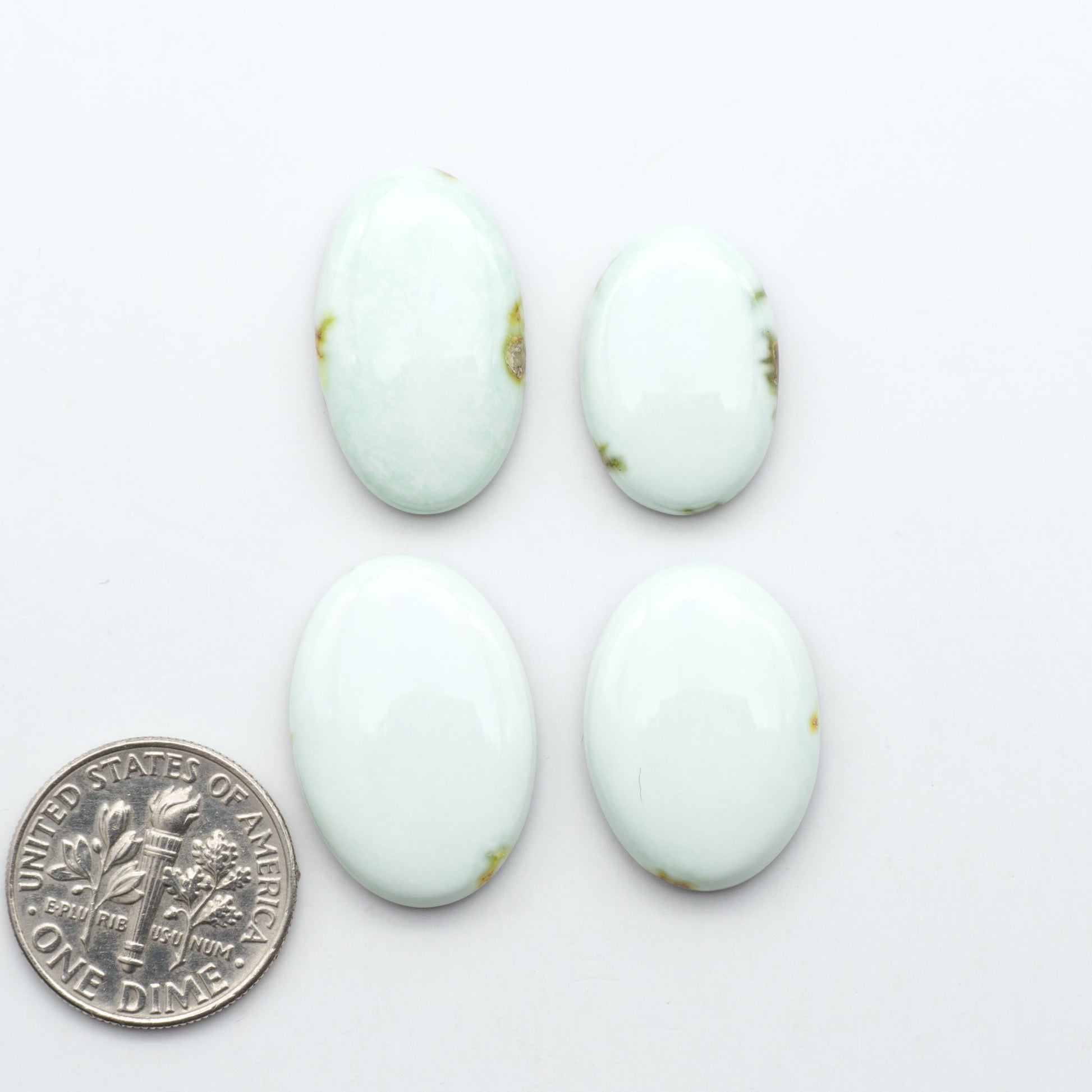 Palomino Variscite cabochons, polished yellow-green gemstones with natural matrix on a white background with a US dime for scale