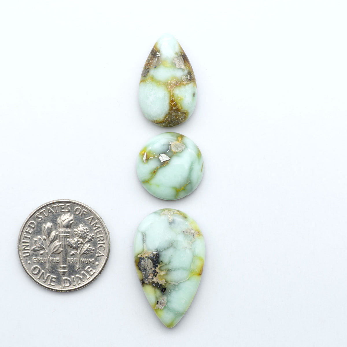 Palomino Variscite cabochons, polished yellow-green gemstones with natural matrix on a white background with a US dime for scale