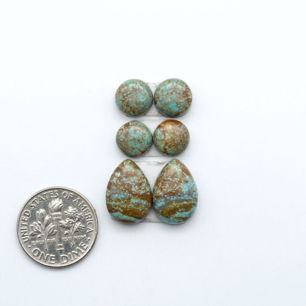 Number 8 Turquoise cabochons, blue and green color with brown matrix, polished stones on a white background, with a US dime for scale