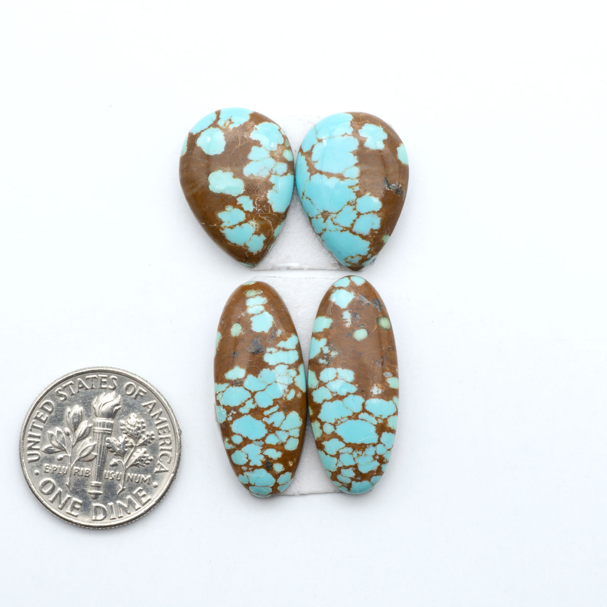 Number 8 Turquoise cabochons, blue and green color with brown matrix, polished stones on a white background, with a US dime for scale