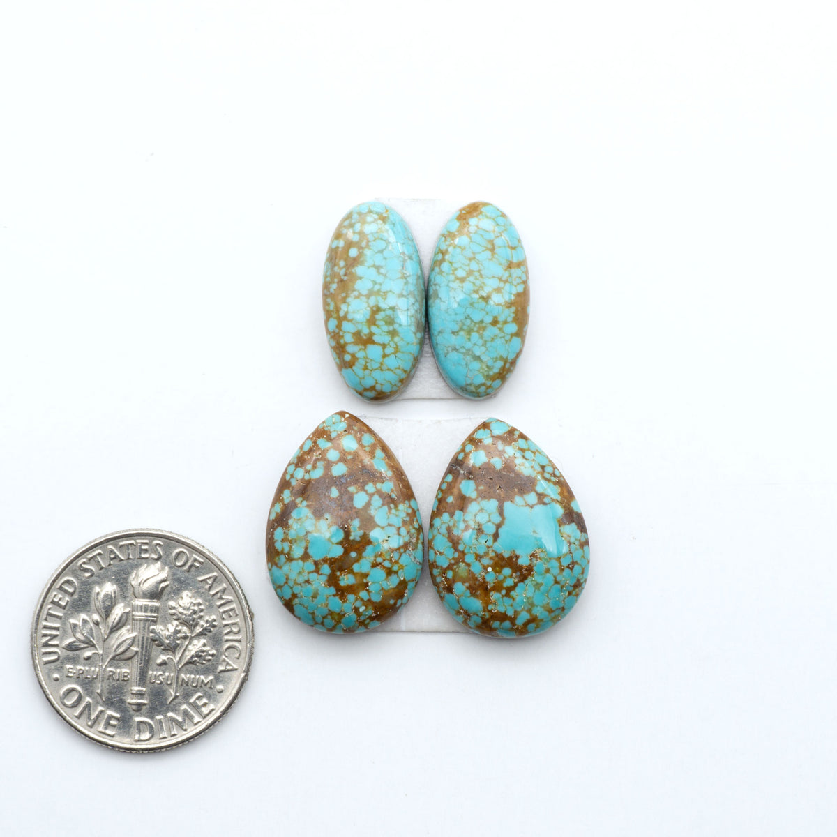 Number 8 Turquoise cabochons, blue and green color with brown matrix, polished stones on a white background, with a US dime for scale