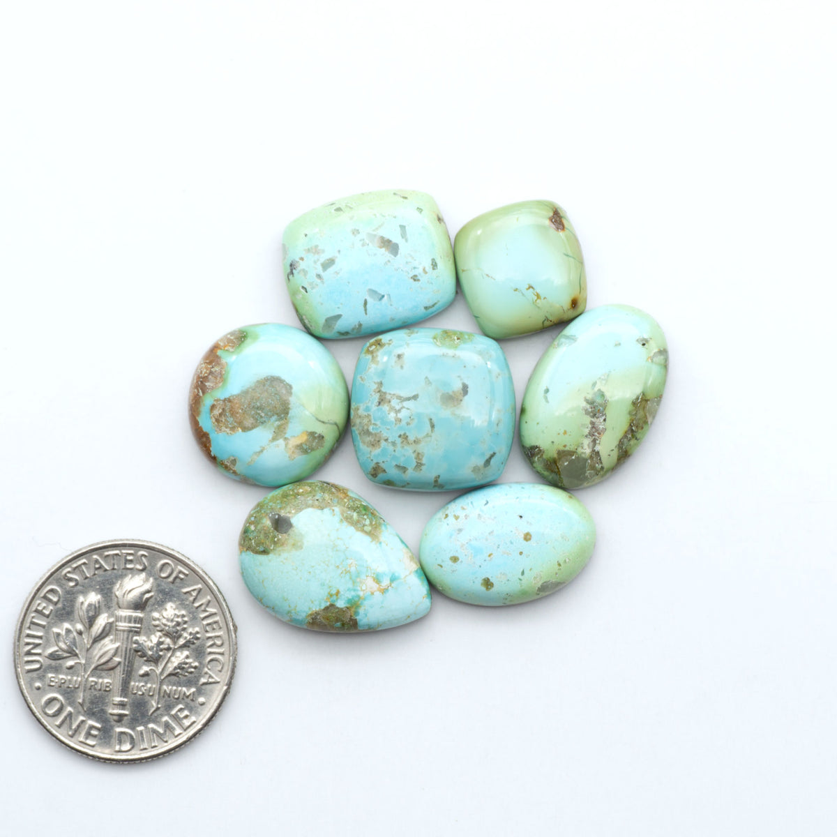 Sonoran Mountain Turquoise cabochons, blue-green color with natural matrix, polished stones on a white background, with a US dime for scale