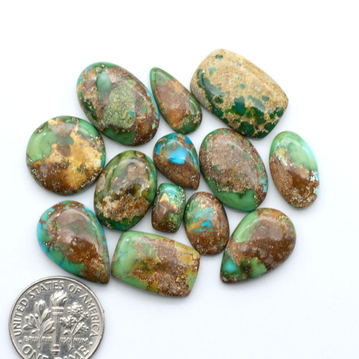 Sonoran Mountain Turquoise cabochons, blue-green color with natural matrix, polished stones on a white background, with a US dime for scale
