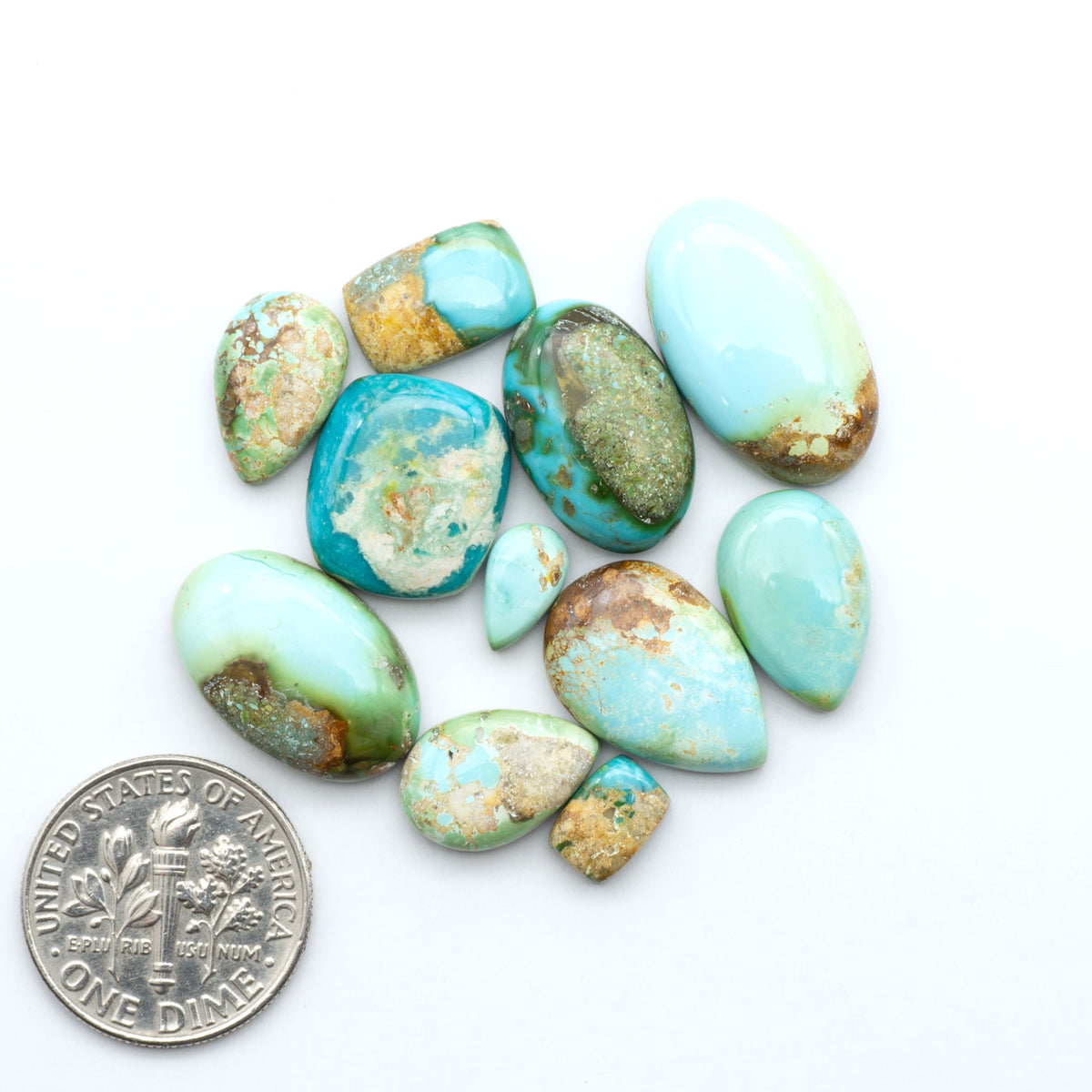 Sonoran Mountain Turquoise cabochons, blue-green color with natural matrix, polished stones on a white background, with a US dime for scale