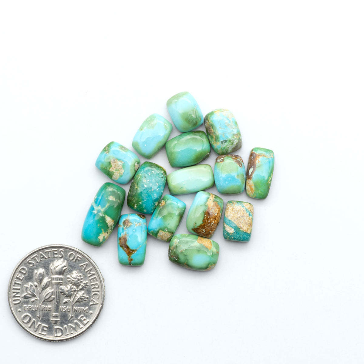 Sonoran Mountain Turquoise cabochons, blue-green color with natural matrix, polished stones on a white background, with a US dime for scale