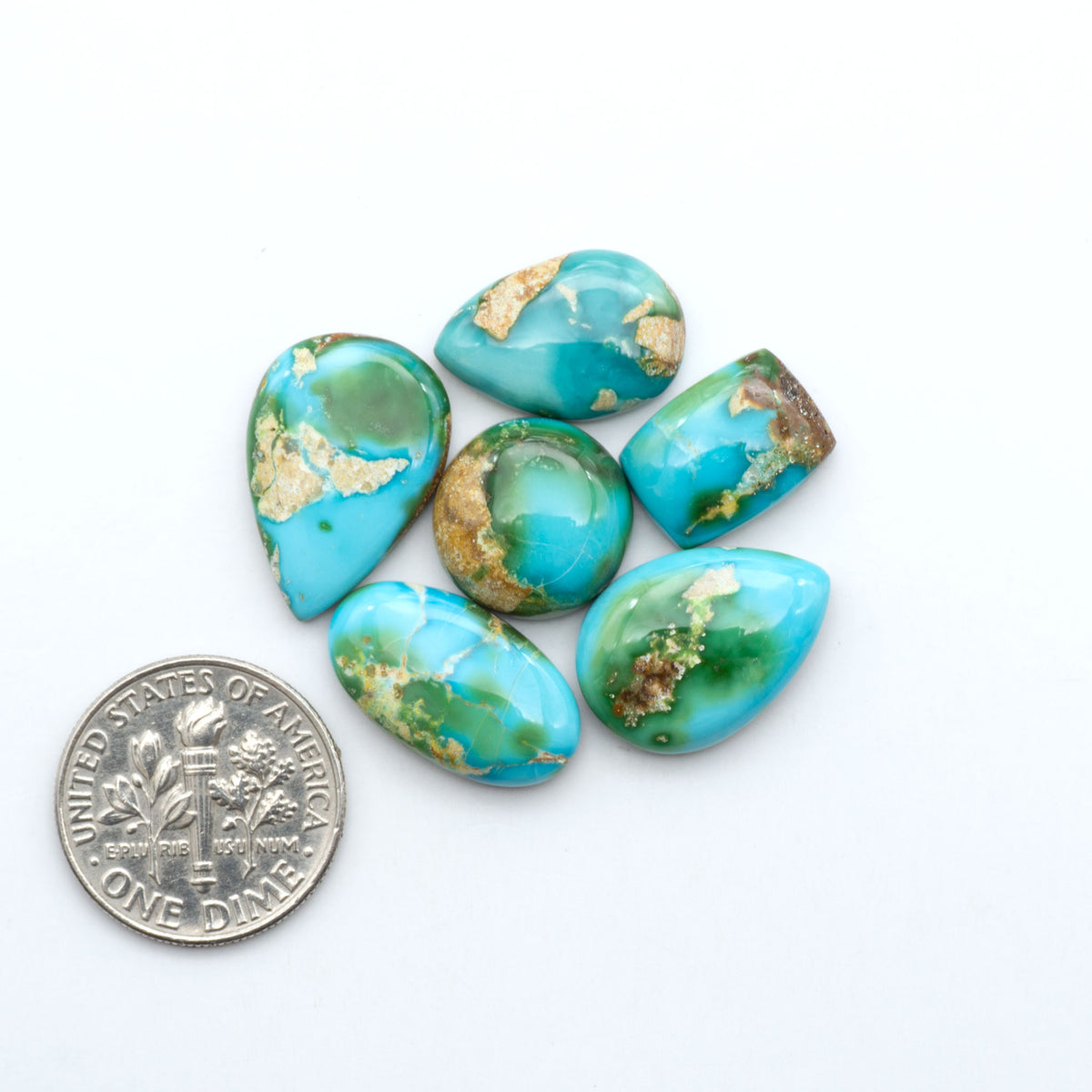Sonoran Mountain Turquoise cabochons, blue-green color with natural matrix, polished stones on a white background, with a US dime for scale