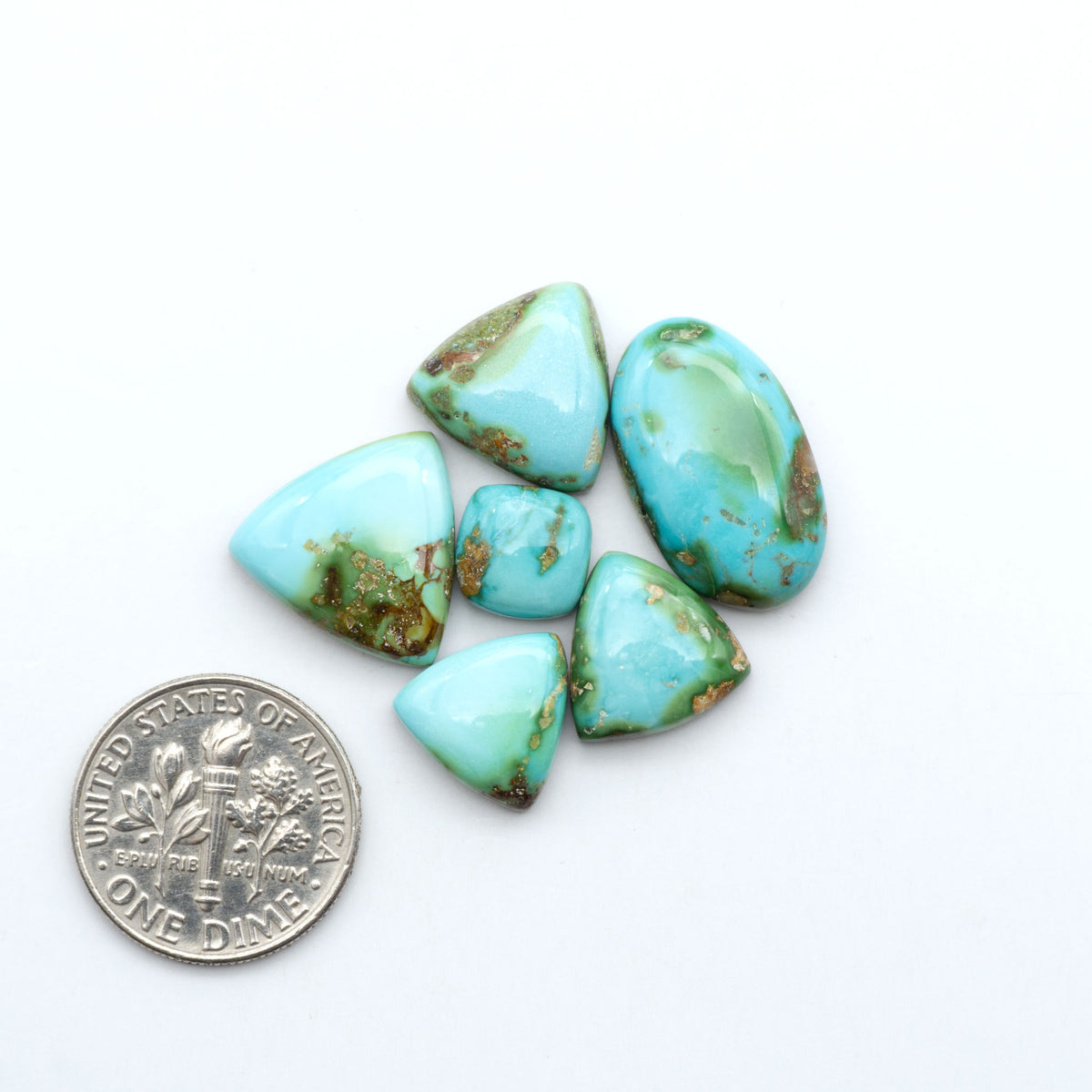 Sonoran Mountain Turquoise cabochons, blue-green color with natural matrix, polished stones on a white background, with a US dime for scale