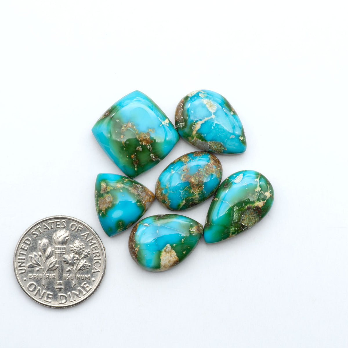 Sonoran Mountain Turquoise cabochons, blue-green color with natural matrix, polished stones on a white background, with a US dime for scale
