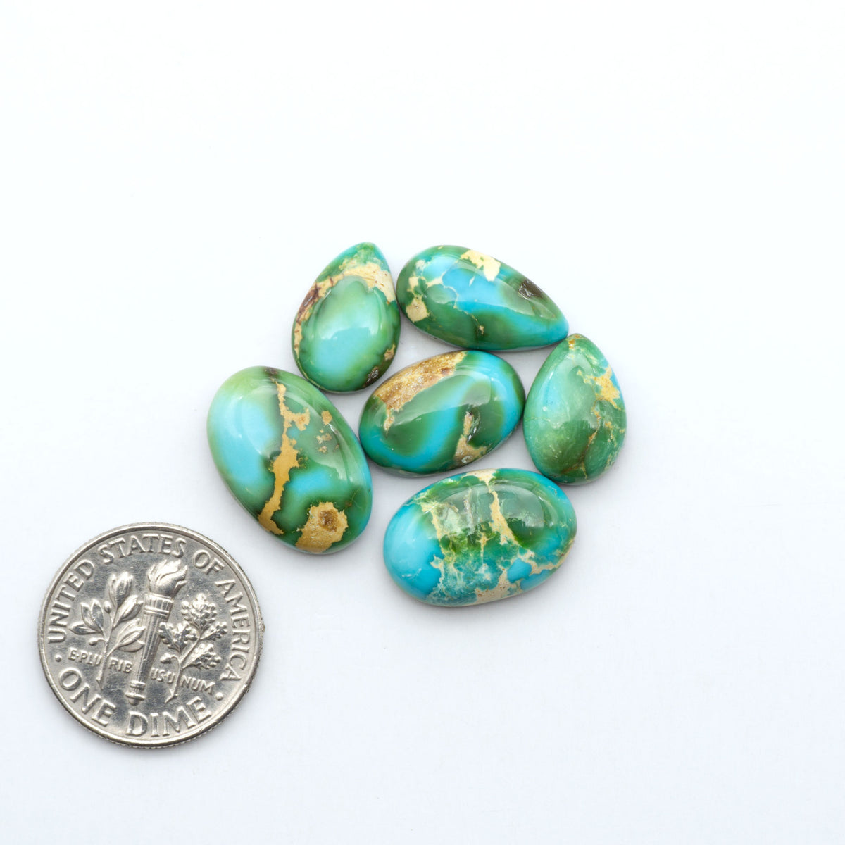 Sonoran Mountain Turquoise cabochons, blue-green color with natural matrix, polished stones on a white background, with a US dime for scale