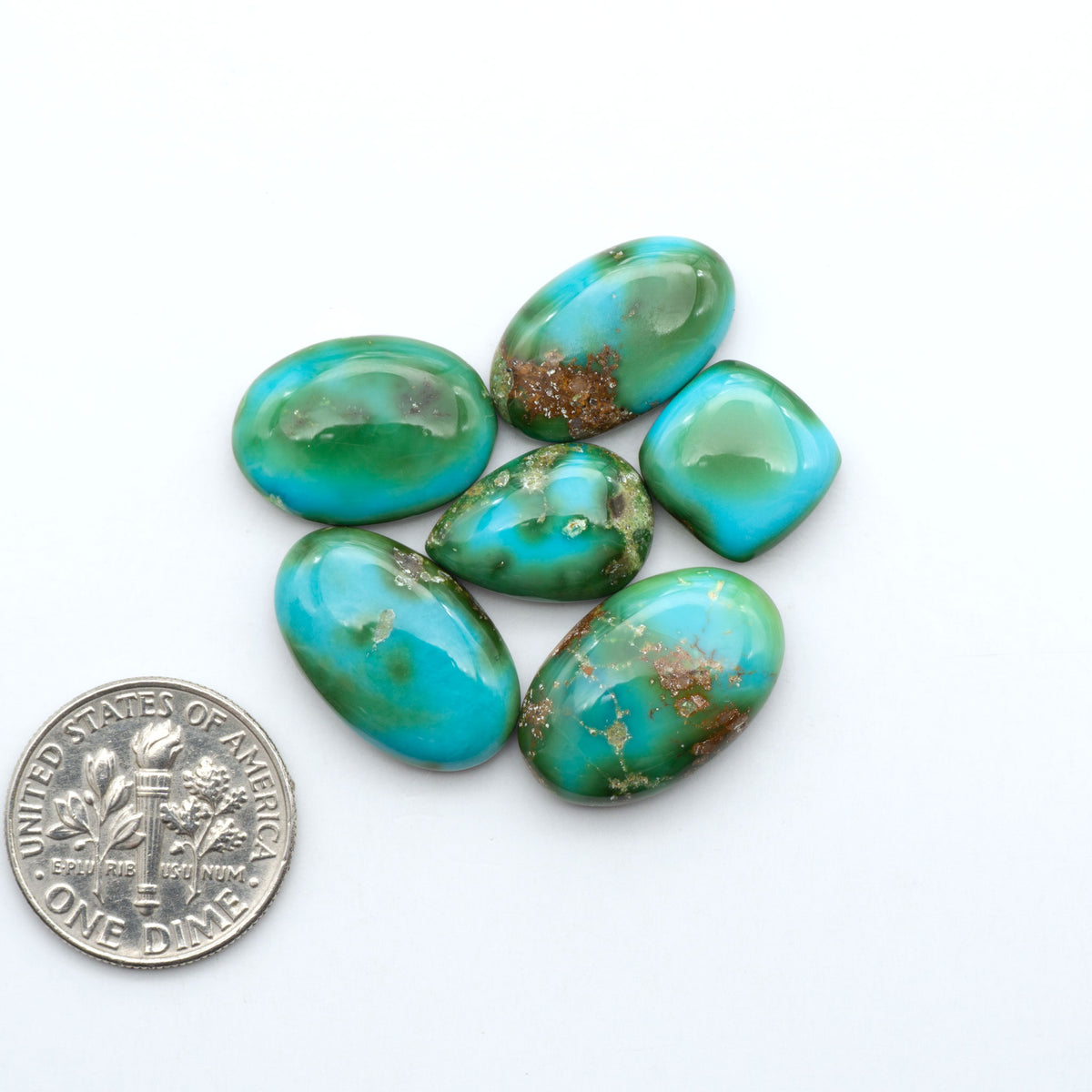 Sonoran Mountain Turquoise cabochons, blue-green color with natural matrix, polished stones on a white background, with a US dime for scale