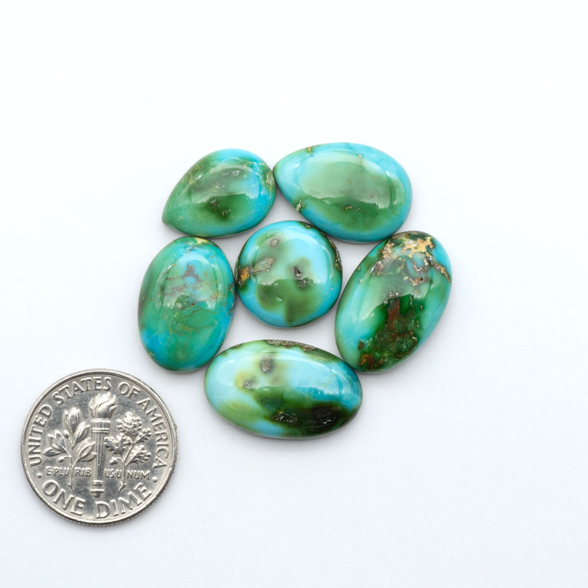 Sonoran Mountain Turquoise cabochons, blue-green color with natural matrix, polished stones on a white background, with a US dime for scale