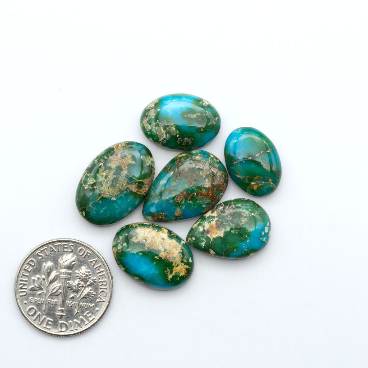 Sonoran Mountain Turquoise cabochons, blue-green color with natural matrix, polished stones on a white background, with a US dime for scale