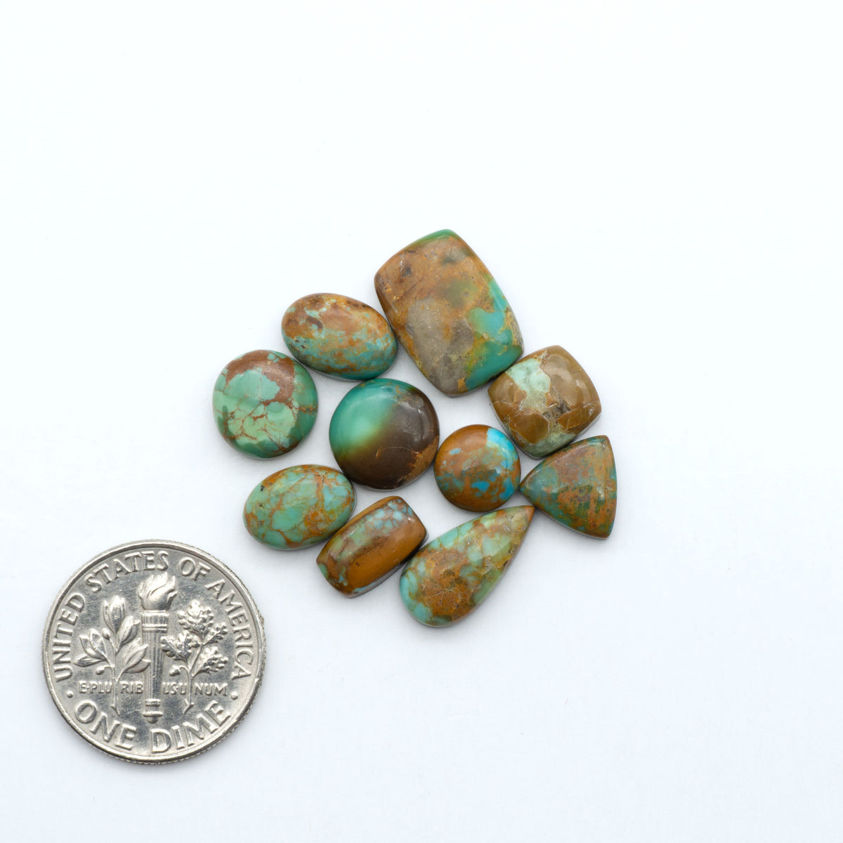 Kings Manassa Turquoise cabochons, polished green-blue gemstones with natural matrix on a white background with a US dime for scale