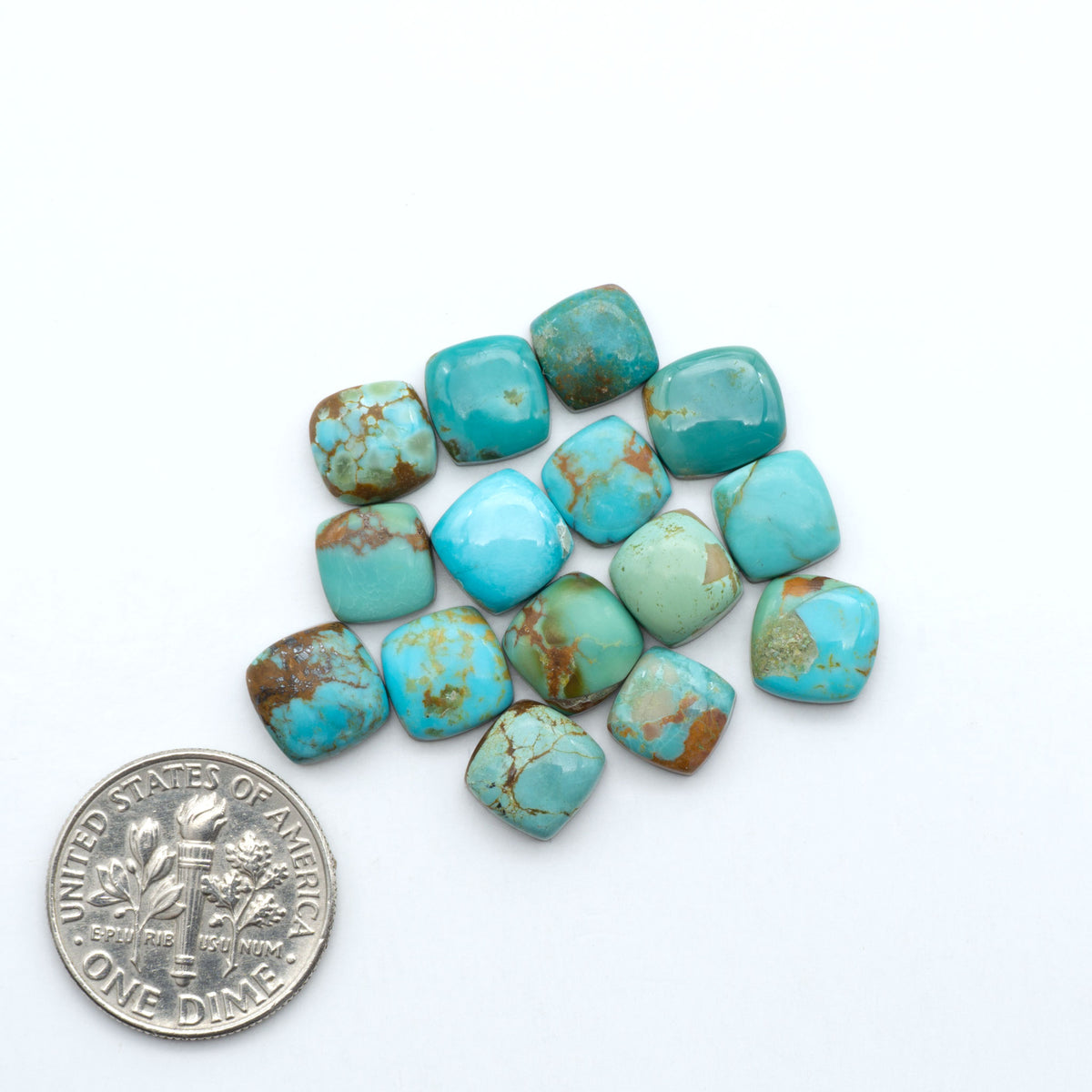 Kings Manassa Turquoise cabochons, polished green-blue gemstones with natural matrix on a white background with a US dime for scale