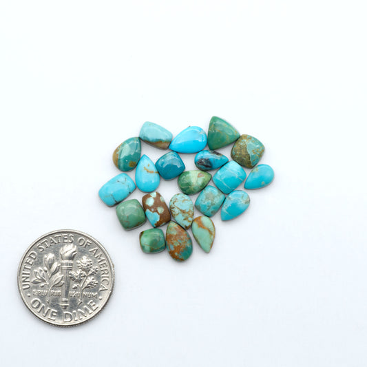 Kings Manassa Turquoise cabochons, polished green-blue gemstones with natural matrix on a white background with a US dime for scale