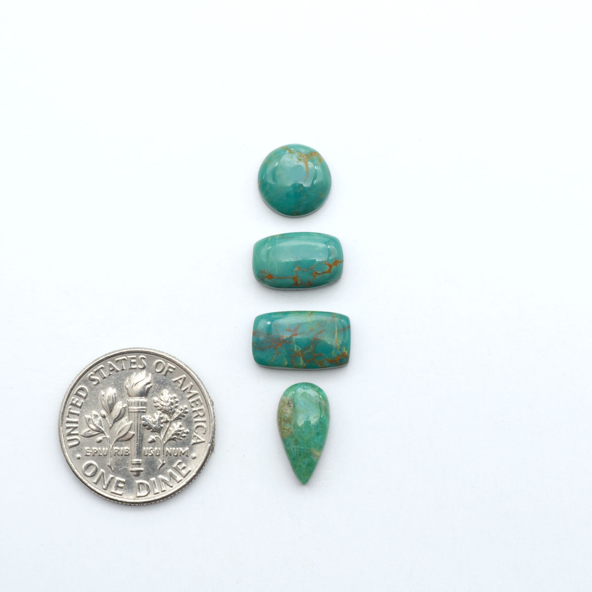 Kings Manassa Turquoise cabochons, polished green-blue gemstones with natural matrix on a white background with a US dime for scale