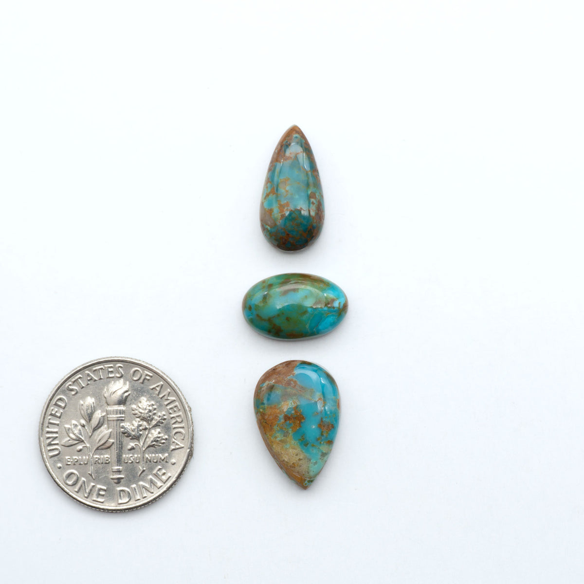 Kings Manassa Turquoise cabochons, polished green-blue gemstones with natural matrix on a white background with a US dime for scale