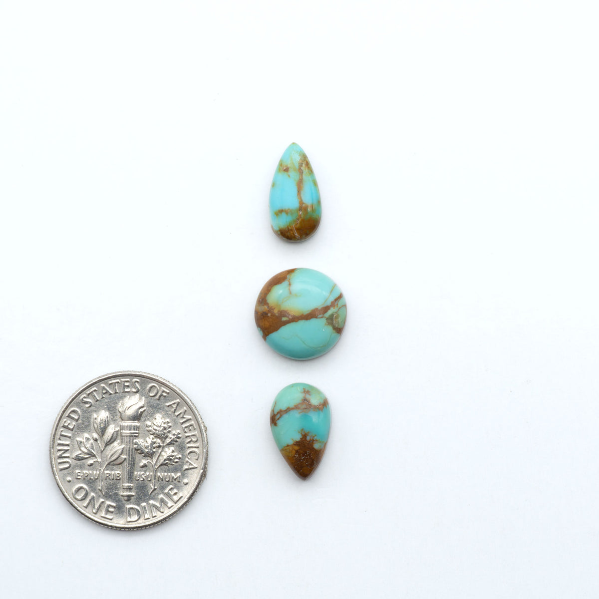 Kings Manassa Turquoise cabochons, polished green-blue gemstones with natural matrix on a white background with a US dime for scale