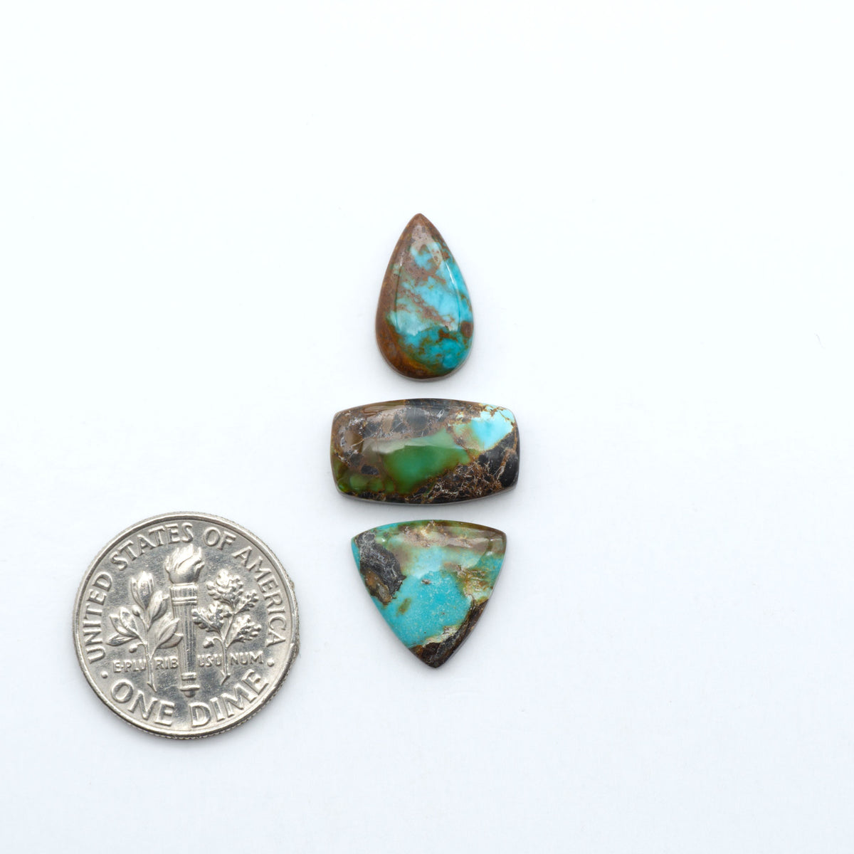 Kings Manassa Turquoise cabochons, polished green-blue gemstones with natural matrix on a white background with a US dime for scale