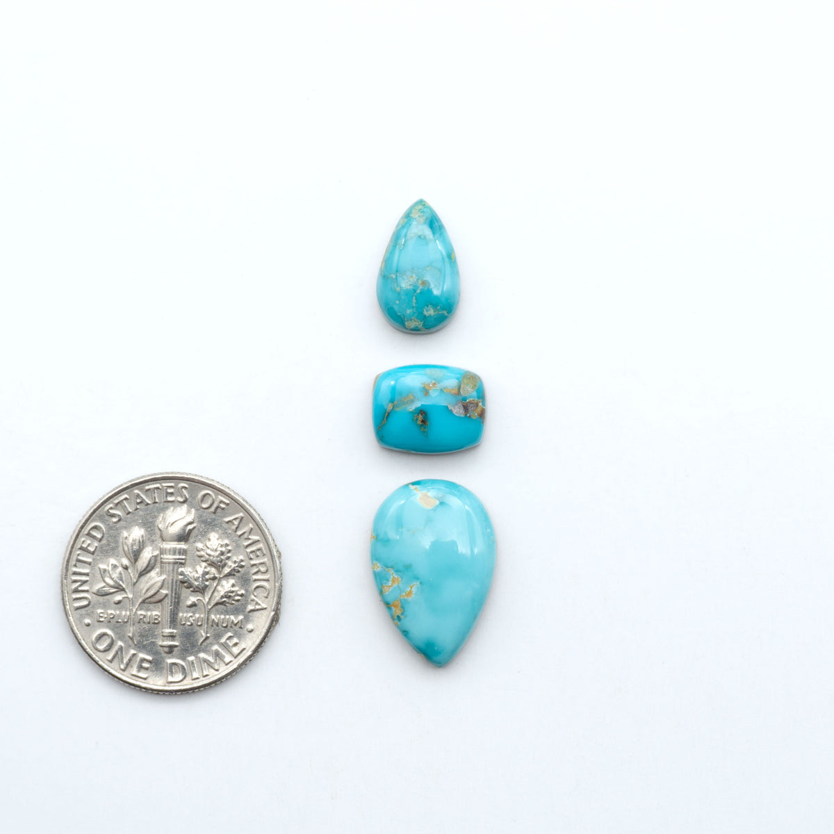 Kings Manassa Turquoise cabochons, polished green-blue gemstones with natural matrix on a white background with a US dime for scale