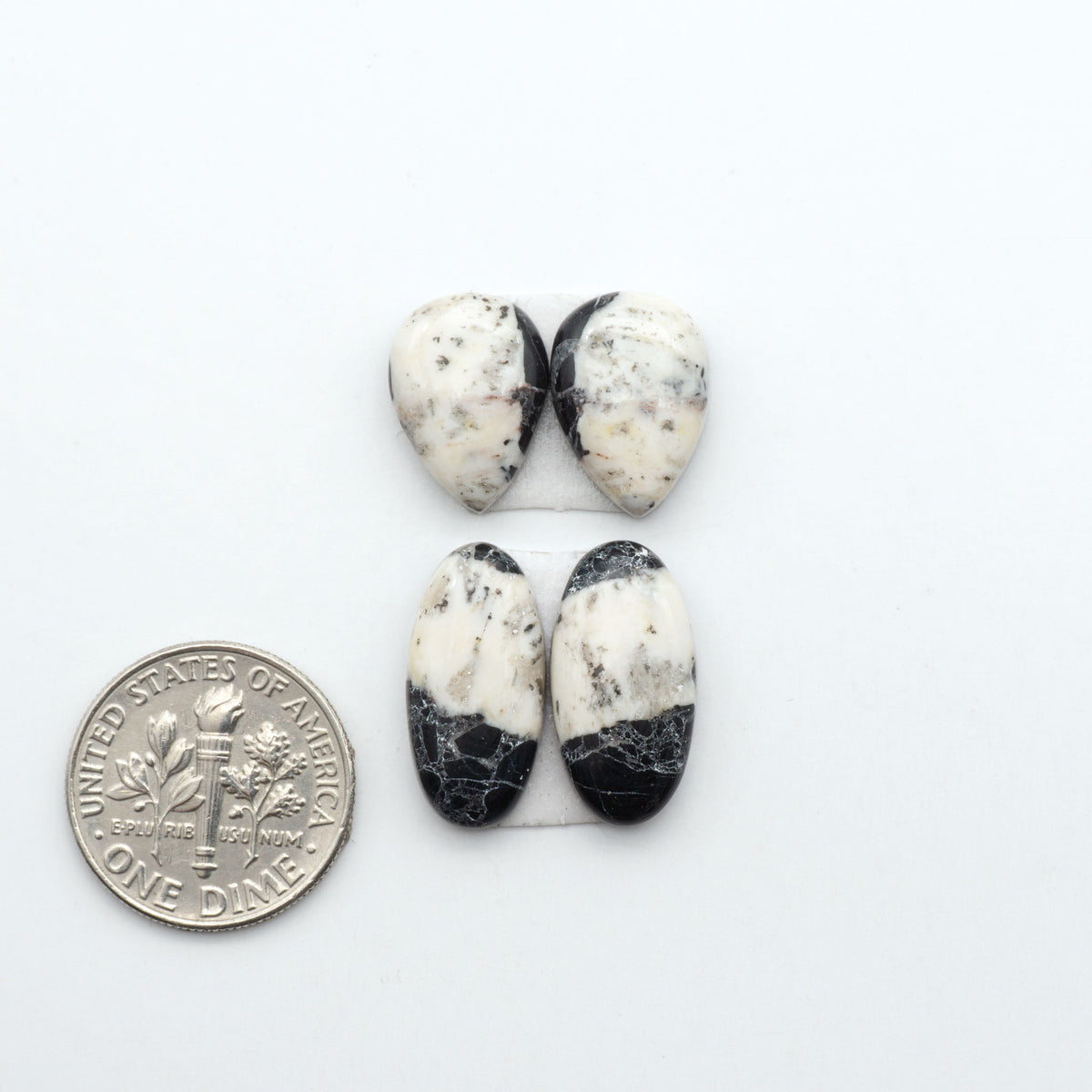 White Buffalo stone cabochons, white stone with black matrix, polished stones on a white background, with a US dime for scale