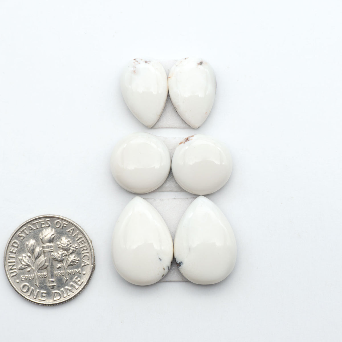 White Buffalo stone cabochons, white stone with black matrix, polished stones on a white background, with a US dime for scale
