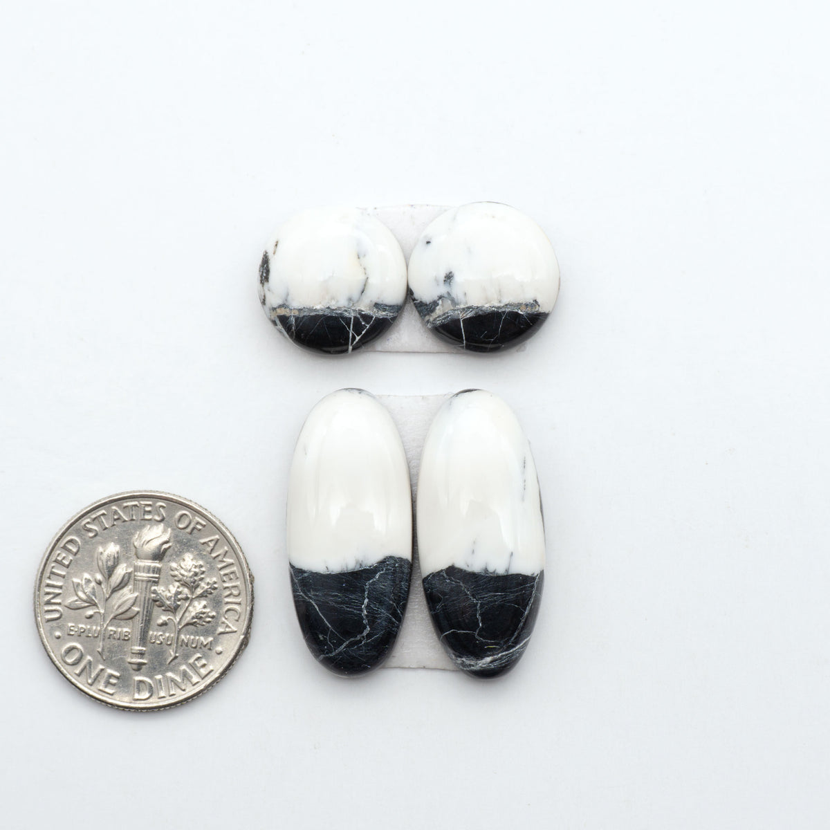 White Buffalo stone cabochons, white stone with black matrix, polished stones on a white background, with a US dime for scale
