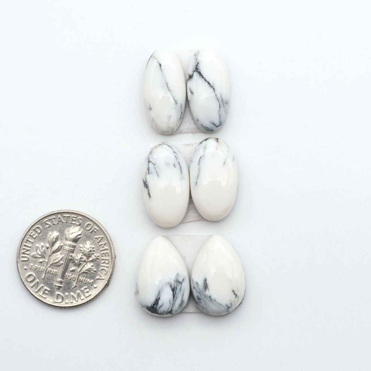 White Buffalo stone cabochons, white stone with black matrix, polished stones on a white background, with a US dime for scale