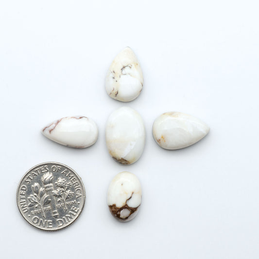 Wild Horse Magnesite cabochons, white gemstones with brown matrix on a white background, with a US dime for scale