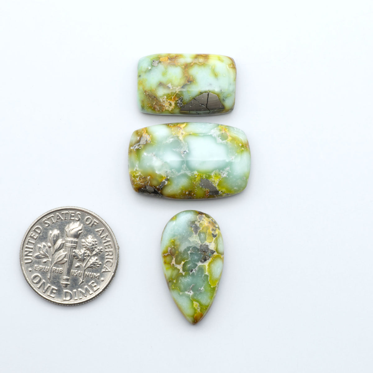 Palomino Variscite cabochons, polished yellow-green gemstones with natural matrix on a white background with a US dime for scale