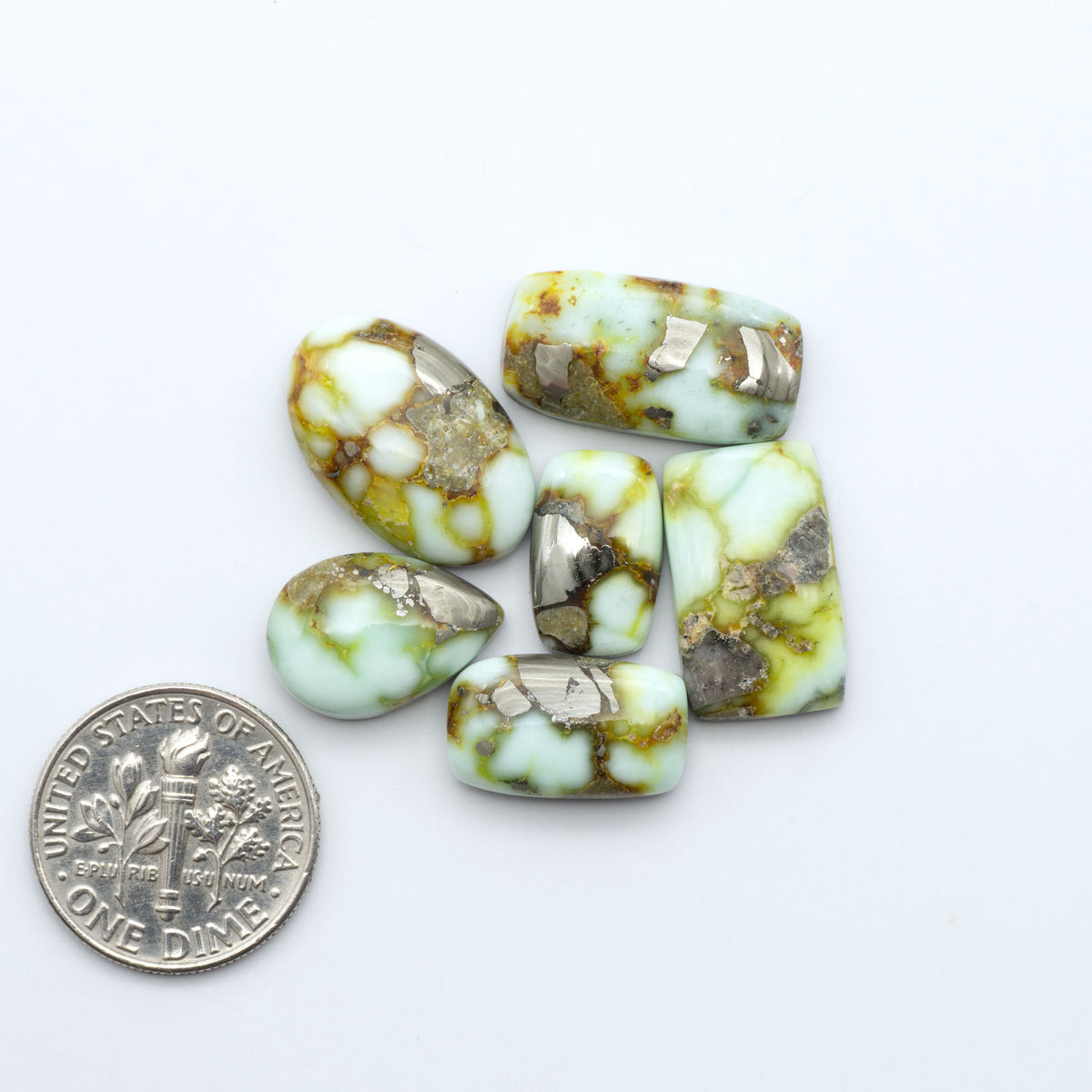 Palomino Variscite cabochons, polished yellow-green gemstones with natural matrix on a white background with a US dime for scale