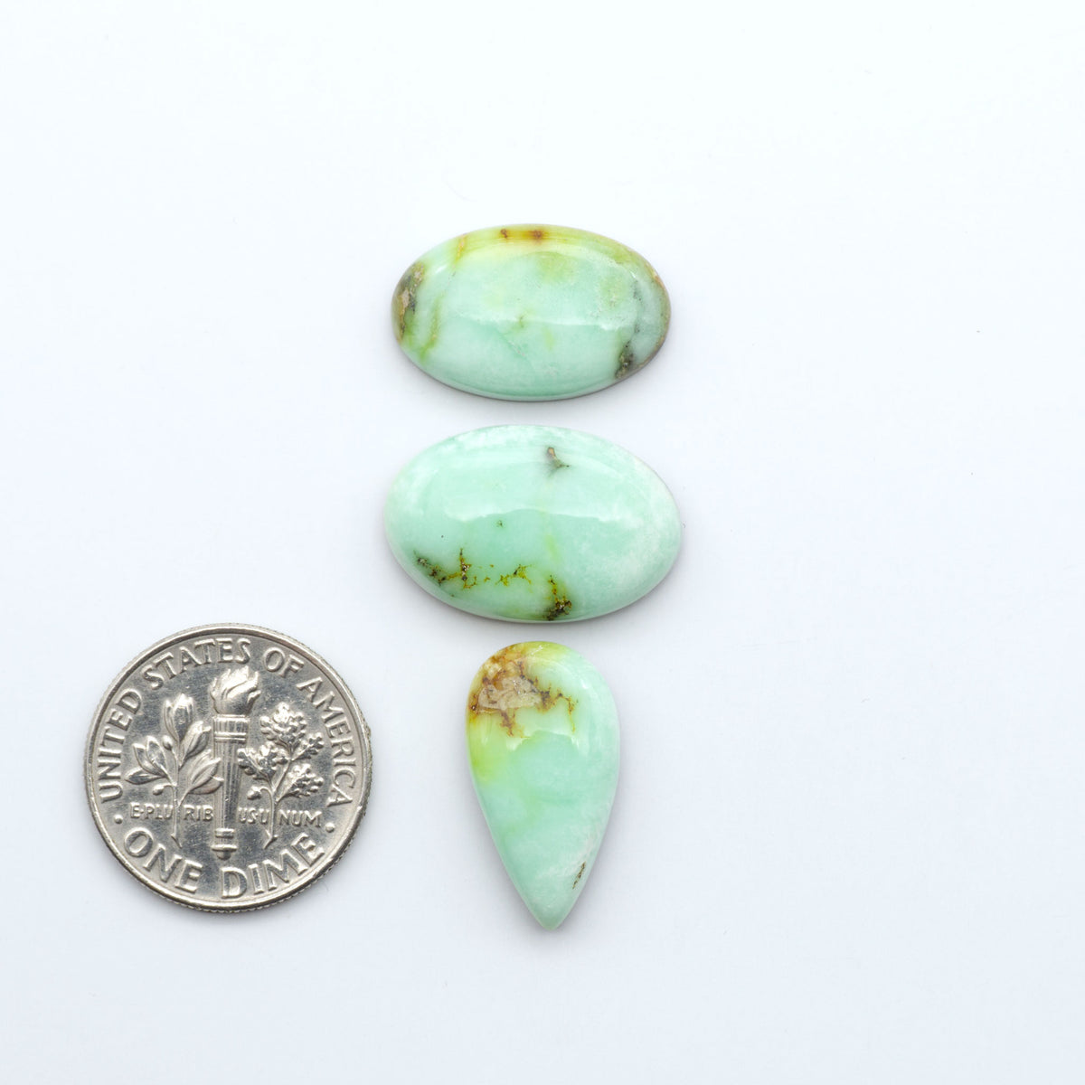 Palomino Variscite cabochons, polished yellow-green gemstones with natural matrix on a white background with a US dime for scale