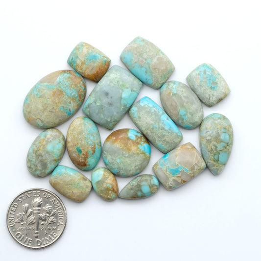 Pilot Mountain Turquoise cabochons, blue-green gemstones with natural matrix on a white background with a US dime for scale