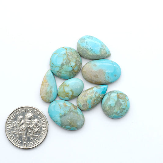 Pilot Mountain Turquoise cabochons, blue-green gemstones with natural matrix on a white background with a US dime for scale