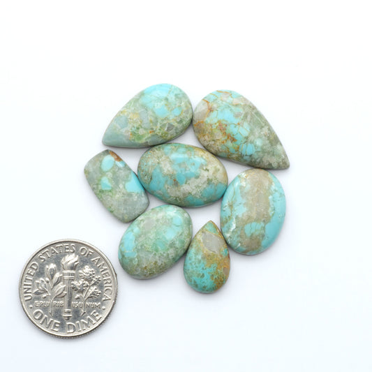 Pilot Mountain Turquoise cabochons, blue-green gemstones with natural matrix on a white background with a US dime for scale