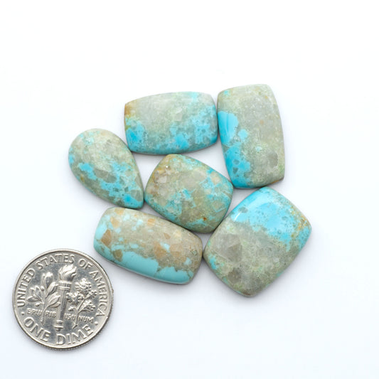 Pilot Mountain Turquoise cabochons, blue-green gemstones with natural matrix on a white background with a US dime for scale