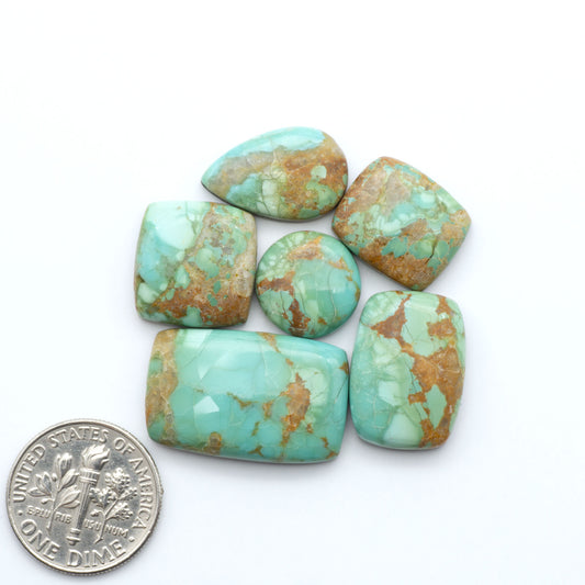 Pilot Mountain Turquoise cabochons, blue-green gemstones with natural matrix on a white background with a US dime for scale