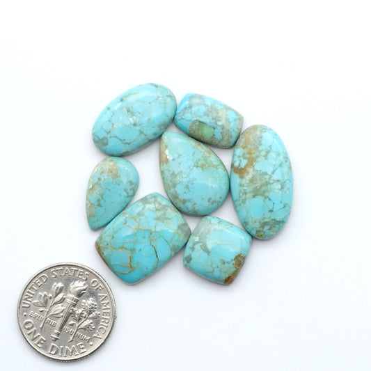 Pilot Mountain Turquoise cabochons, blue-green gemstones with natural matrix on a white background with a US dime for scale