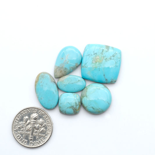 Pilot Mountain Turquoise cabochons, blue-green gemstones with natural matrix on a white background with a US dime for scale