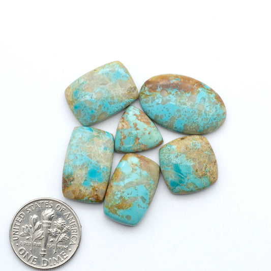 Pilot Mountain Turquoise cabochons, blue-green gemstones with natural matrix on a white background with a US dime for scale