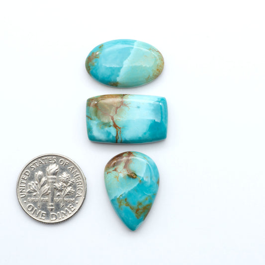 Pilot Mountain Turquoise cabochons, blue-green gemstones with natural matrix on a white background with a US dime for scale