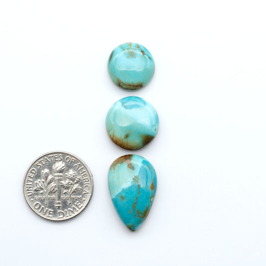 Pilot Mountain Turquoise cabochons, blue-green gemstones with natural matrix on a white background with a US dime for scale