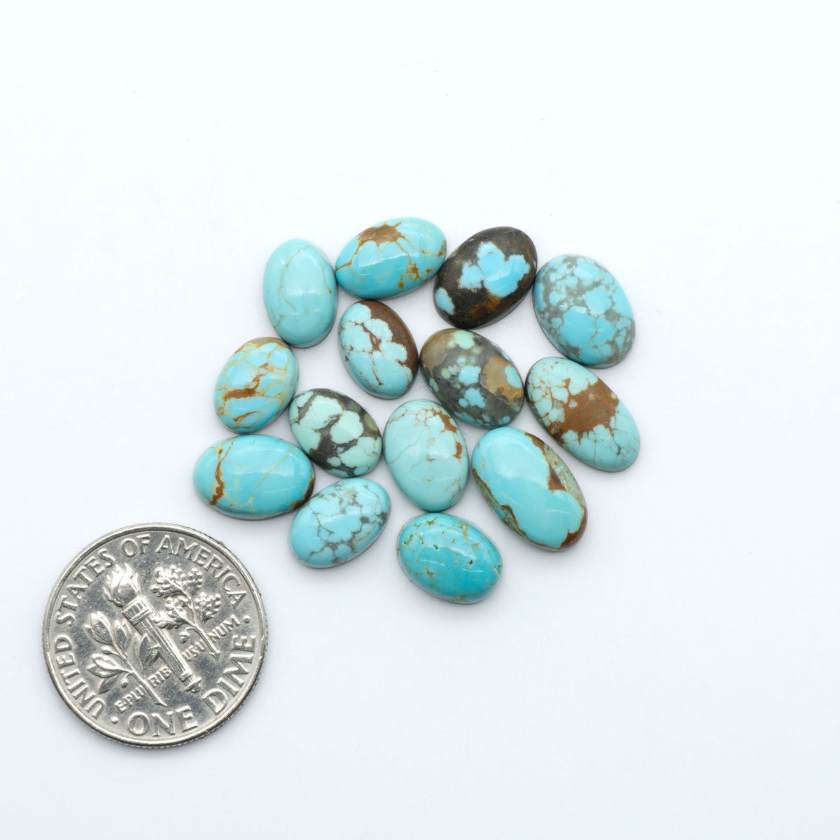 Number 8 Turquoise cabochons, blue and green color with brown matrix, polished stones on a white background, with a US dime for scale
