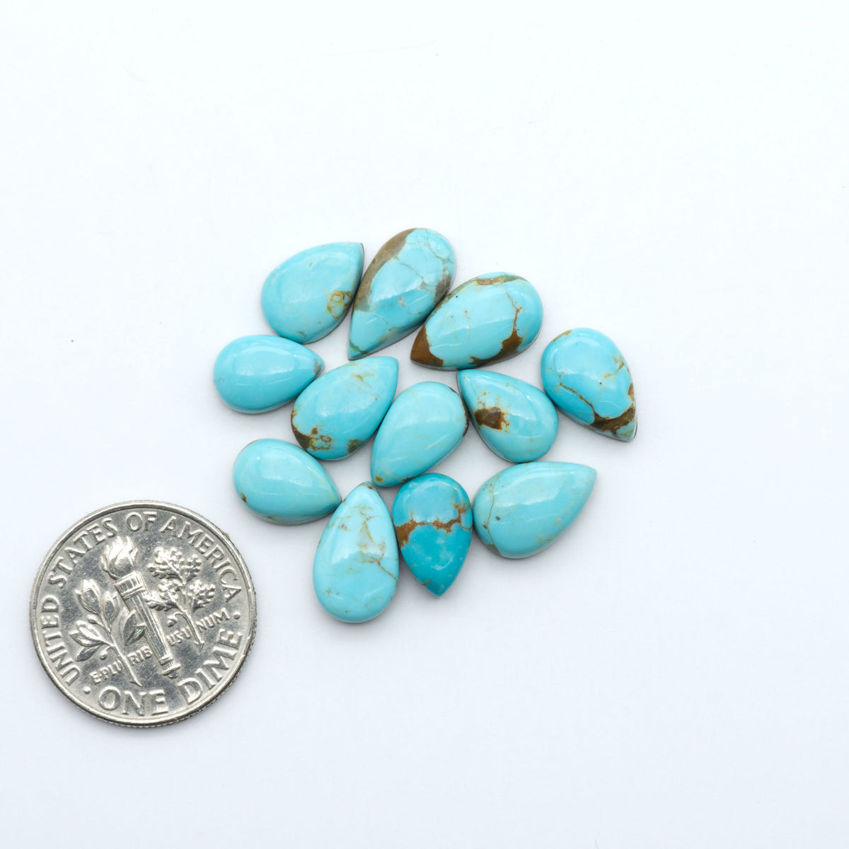 Number 8 Turquoise cabochons, blue and green color with brown matrix, polished stones on a white background, with a US dime for scale