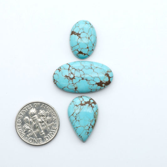 Number 8 Turquoise cabochons, blue and green color with brown matrix, polished stones on a white background, with a US dime for scale