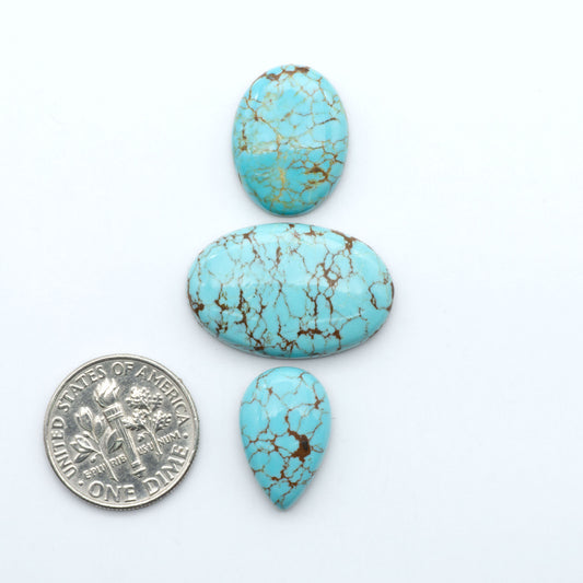 Number 8 Turquoise cabochons, blue and green color with brown matrix, polished stones on a white background, with a US dime for scale