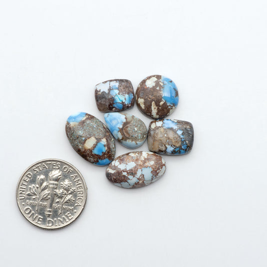 Golden Hills Turquoise cabochons, icy blue to lavender tones with chocolate matrix, polished stones on a white background with a US dime for scale