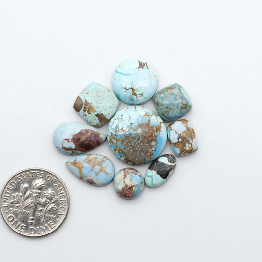 Golden Hills Turquoise cabochons, icy blue to lavender tones with chocolate matrix, polished stones on a white background with a US dime for scale