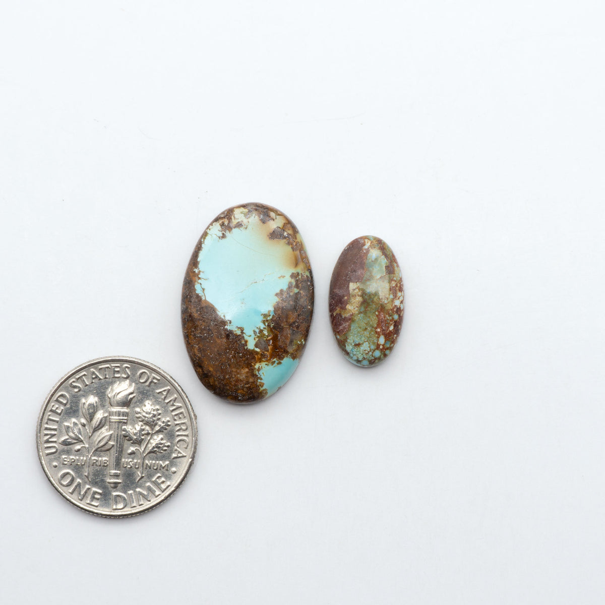 Golden Hills Turquoise cabochons, icy blue to lavender tones with chocolate matrix, polished stones on a white background with a US dime for scale